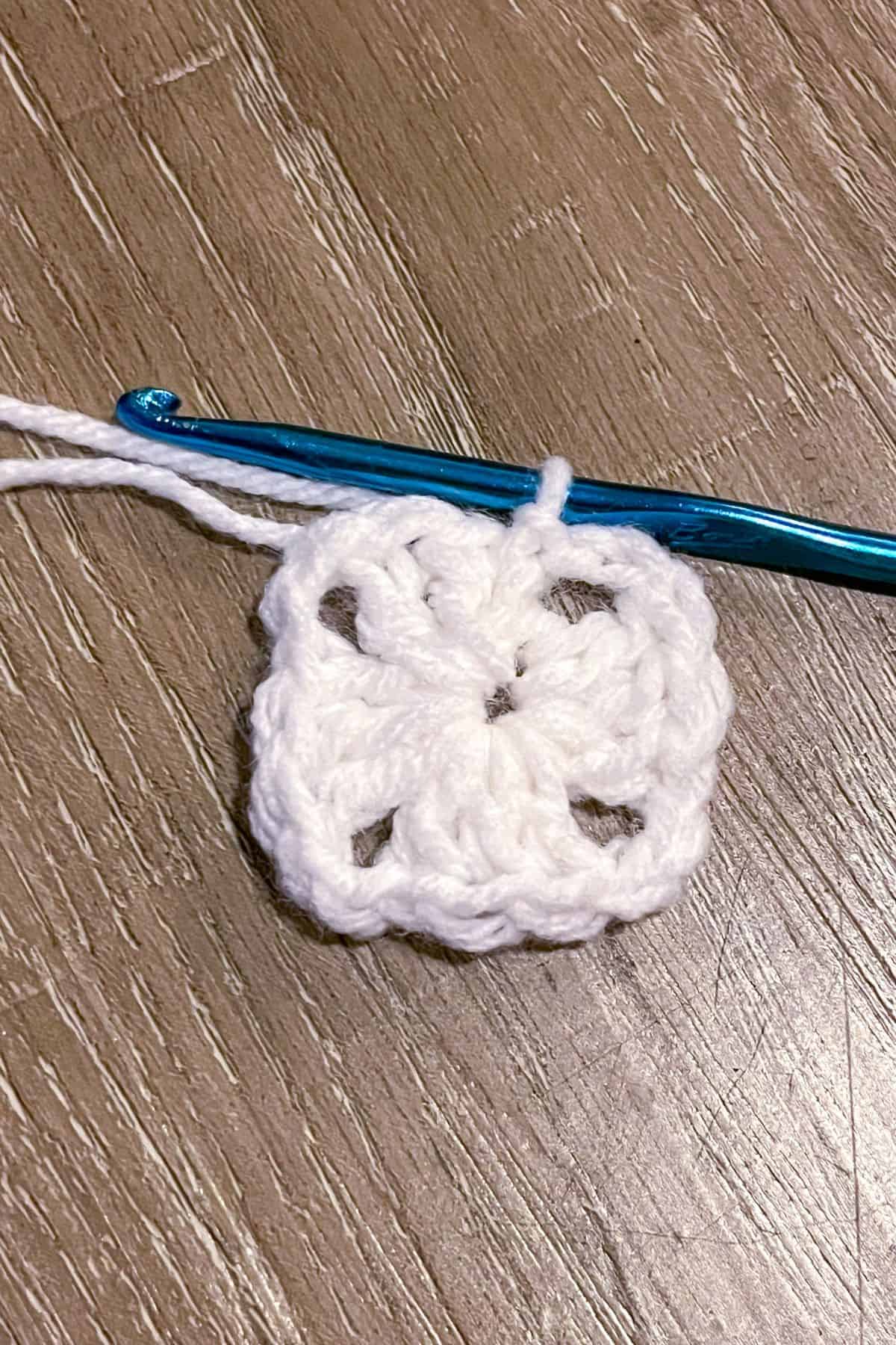 The start of a crochet granny square using white yarn.