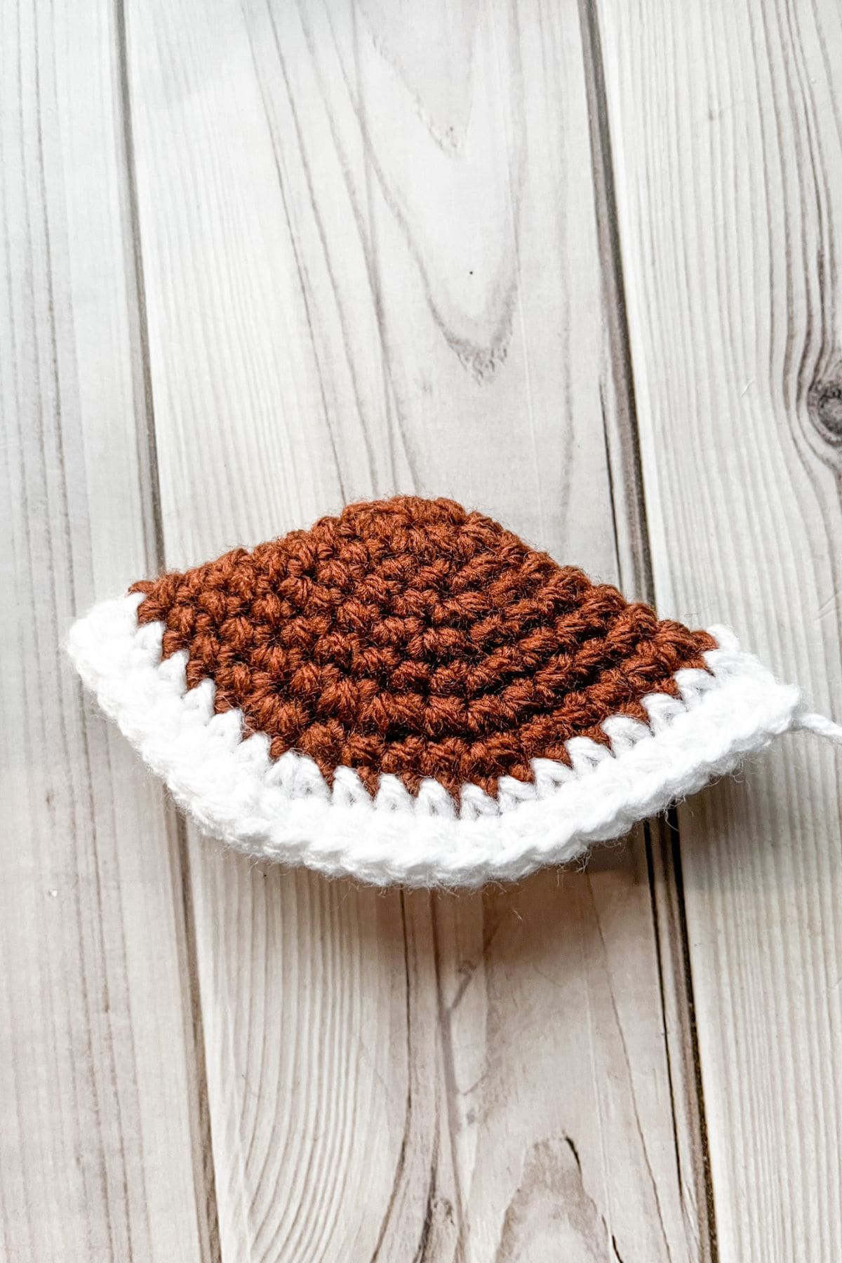 Adding the first white stripe to the crochet football.