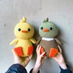 2 ducks are being held up to a plain background.