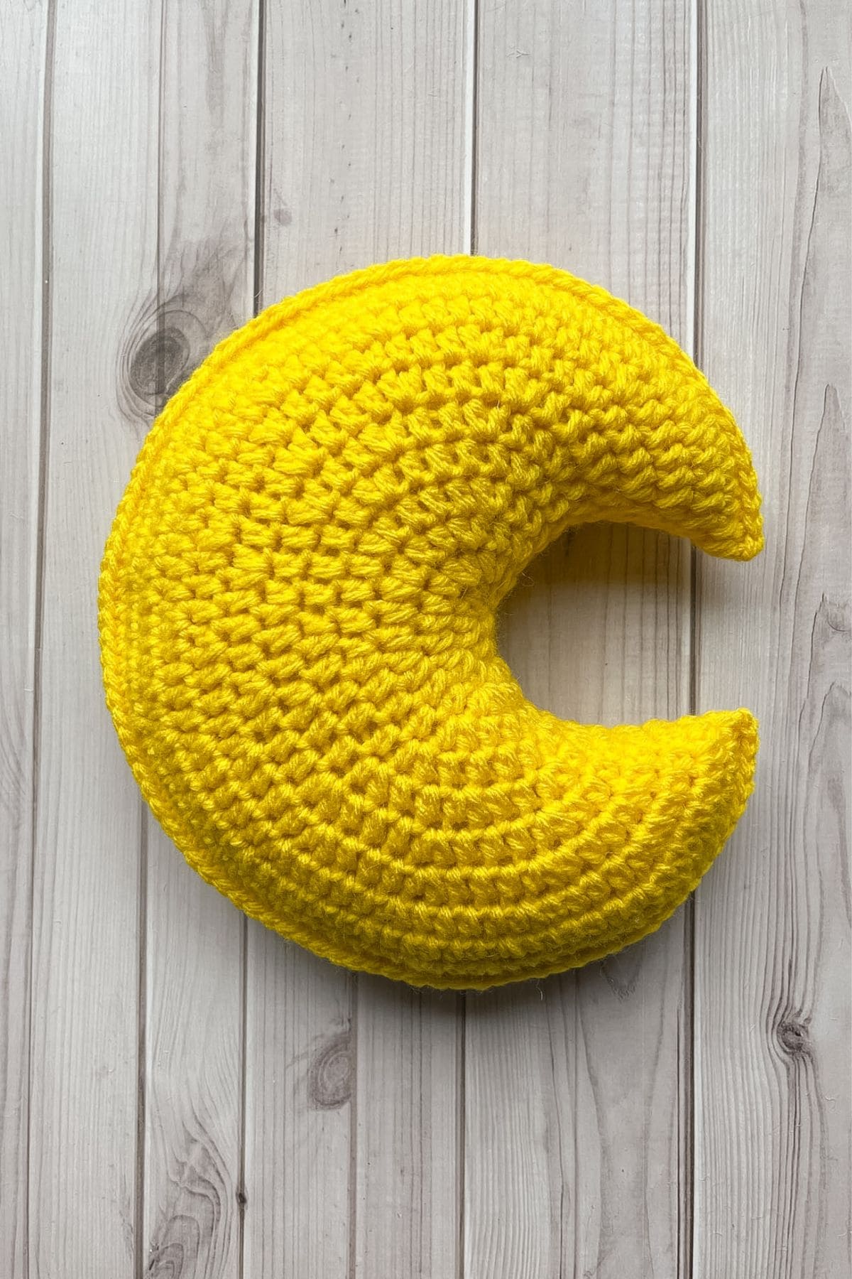 Finished crochet moon pillow on table.