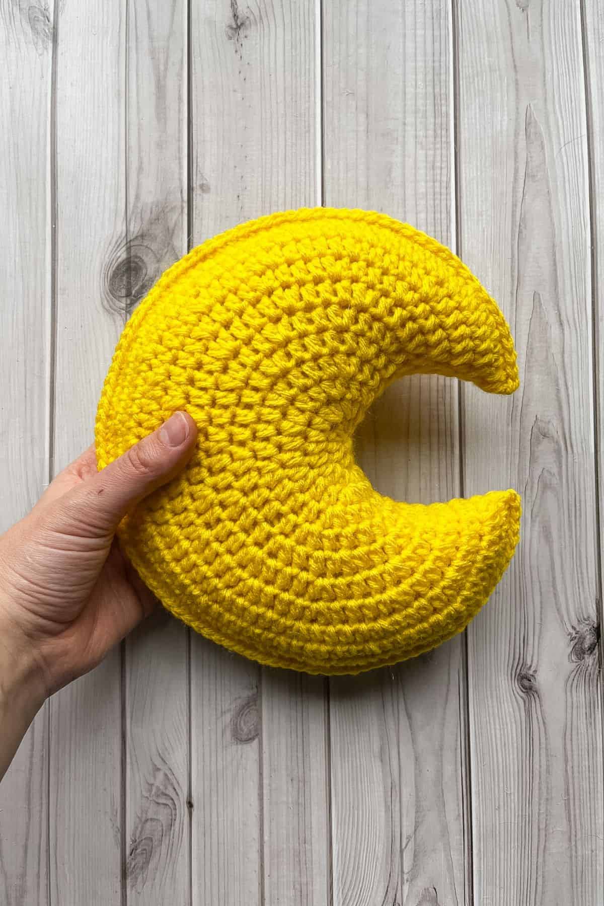 Finished crochet moon pillow on table.