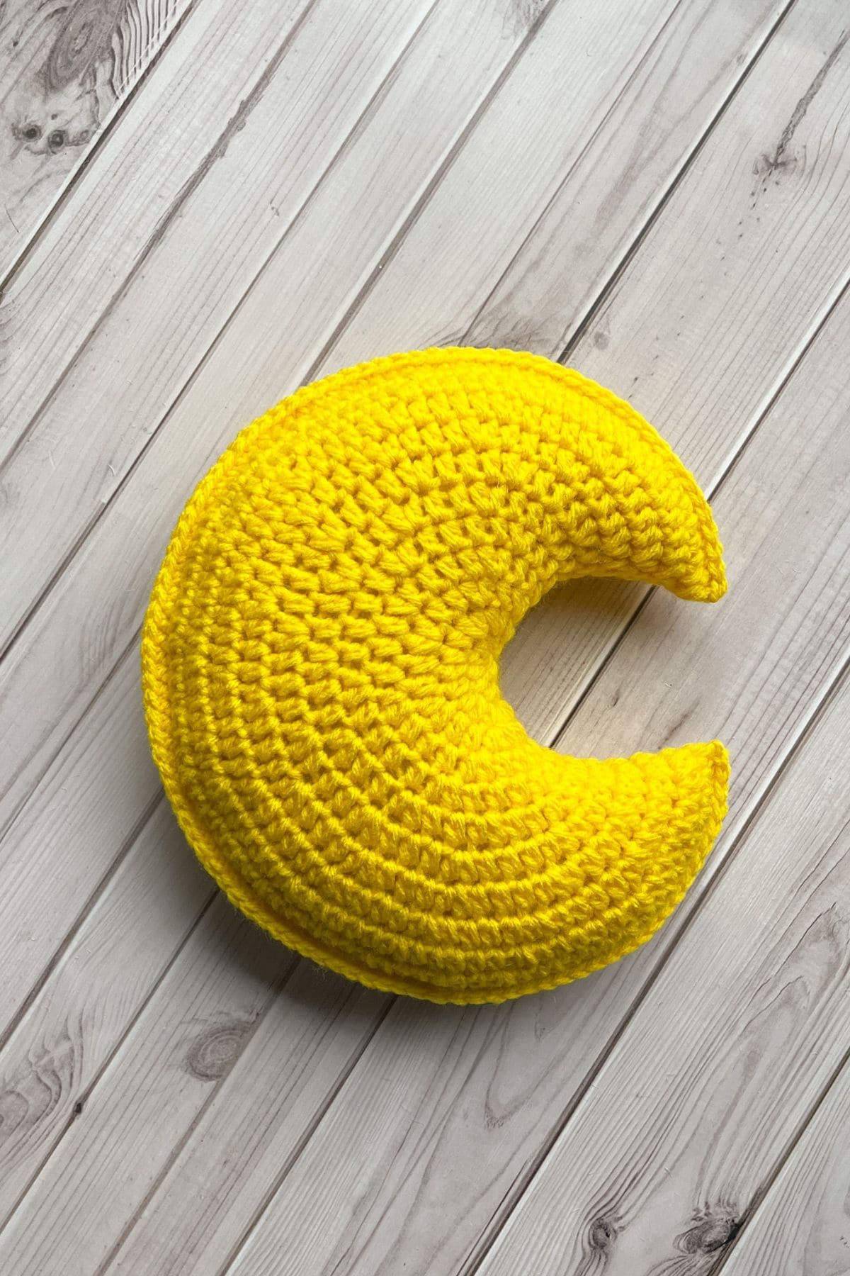 Finished crochet moon pillow on table.