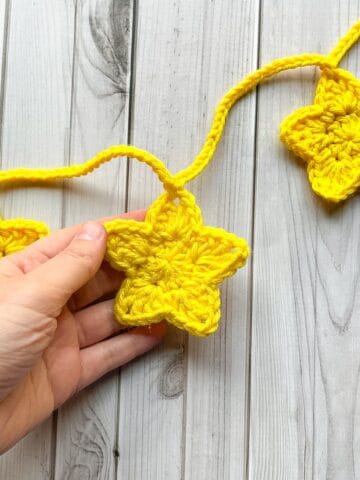 Crochet star garland in hand above a table.
