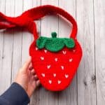 Finished crochet strawberry bag on table.