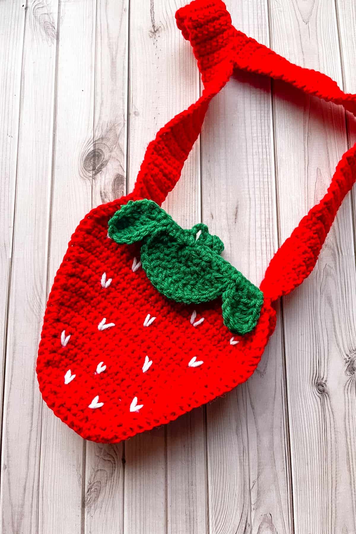 Finished crochet strawberry bag on table.