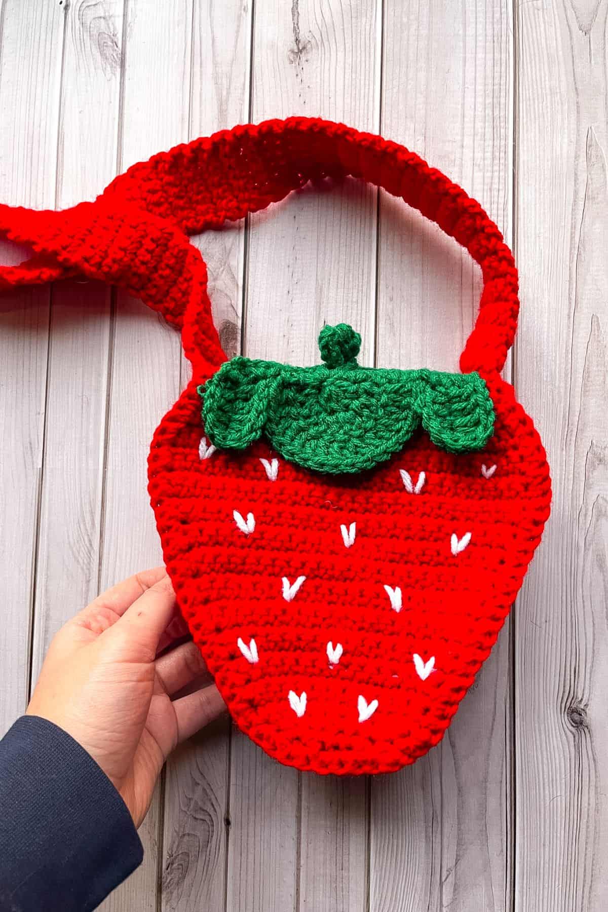 Finished crochet strawberry bag on table.