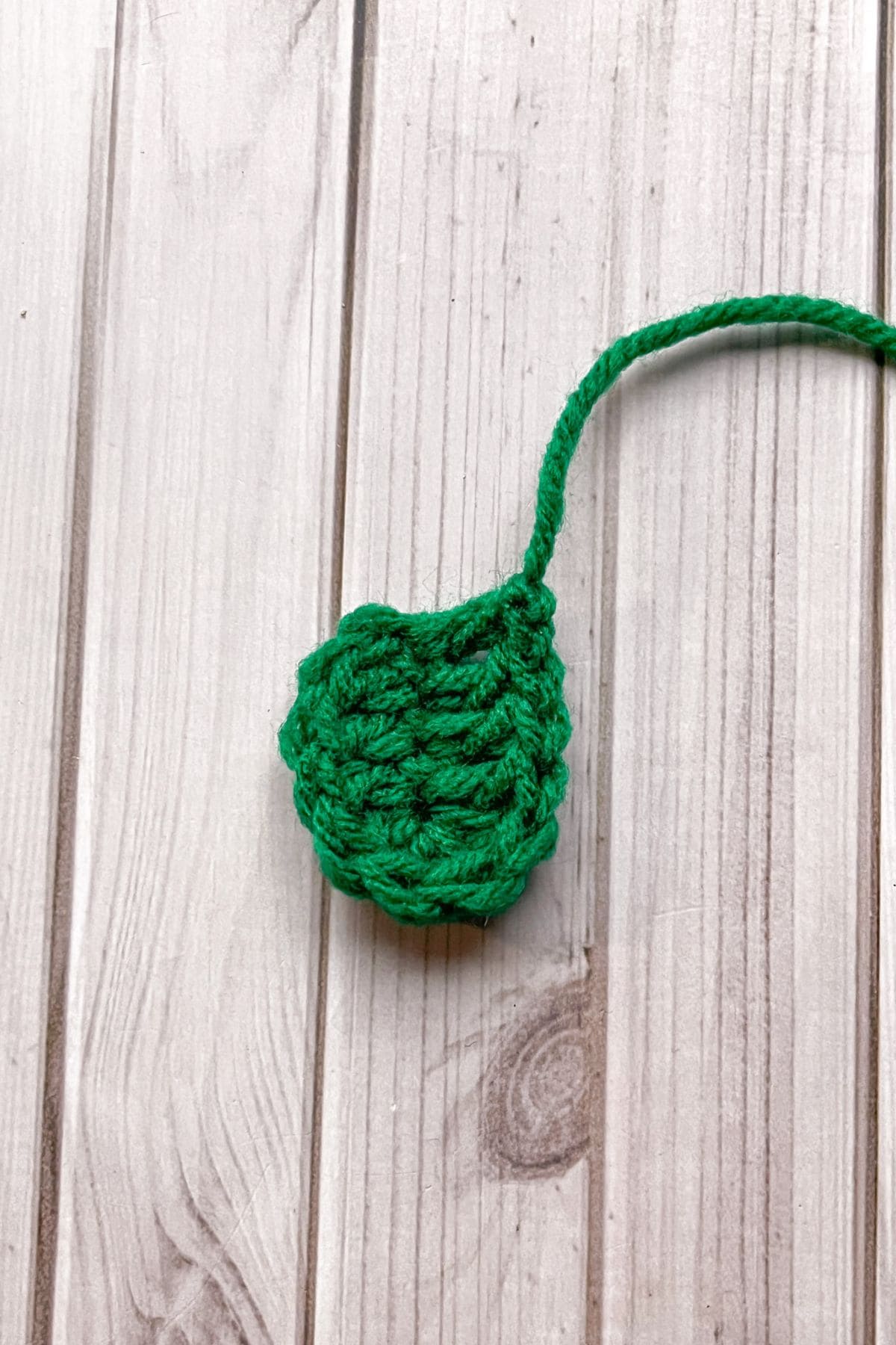 Small strawberry crochet leaf on table.