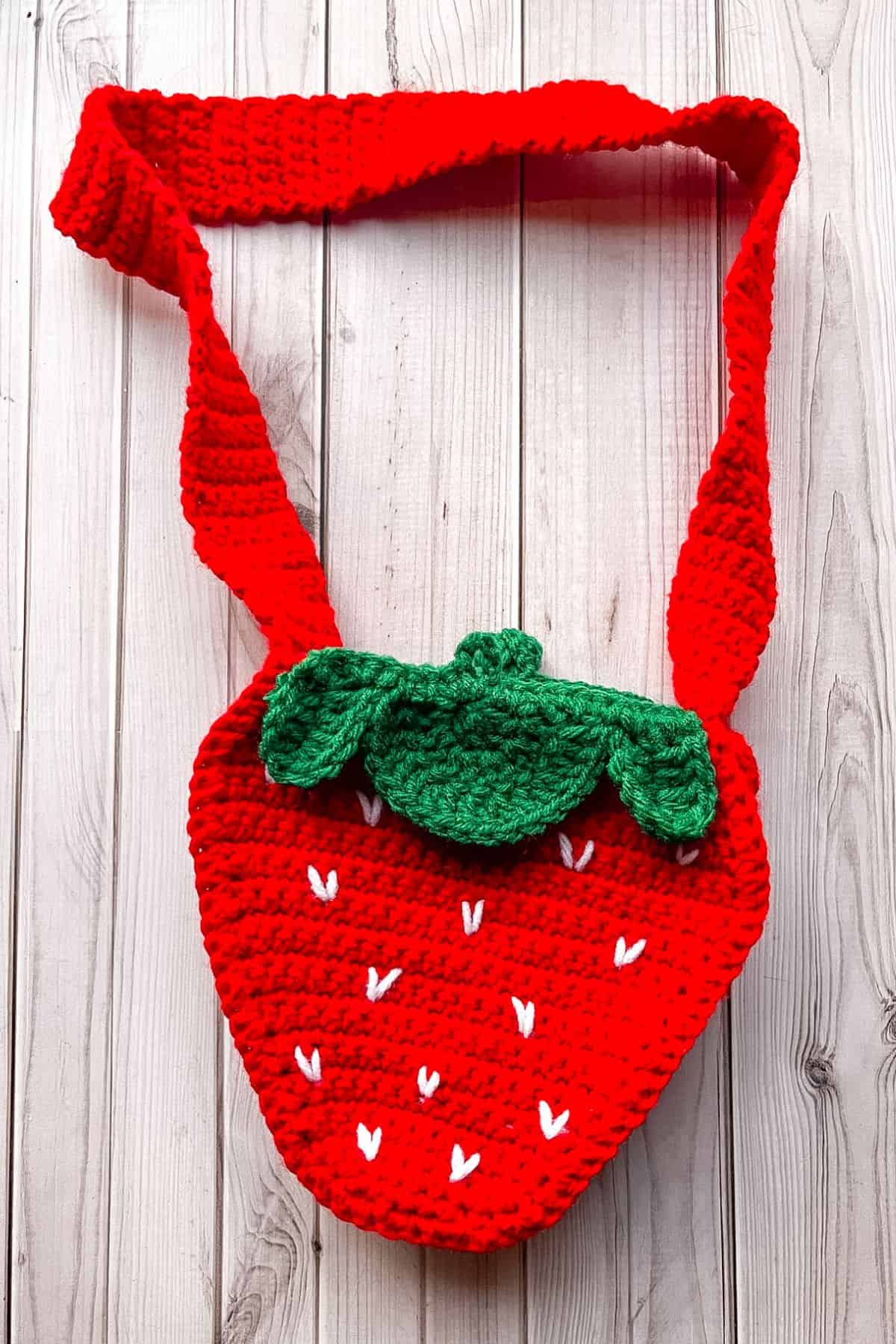 Finished crochet strawberry bag on table.