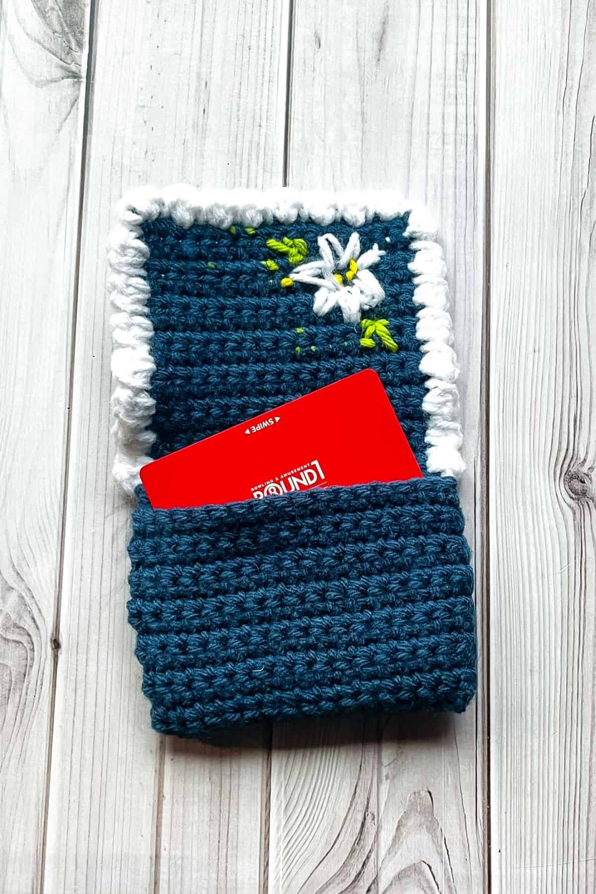 Finished crochet wallet with arcade gift card on table.