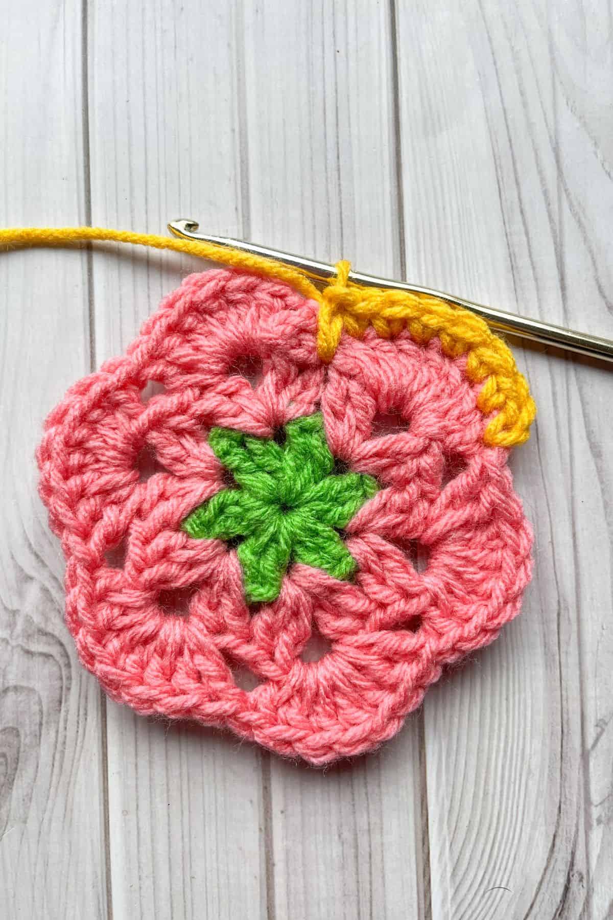 Starting round 4 with yellow yarn, lays on table with hook.