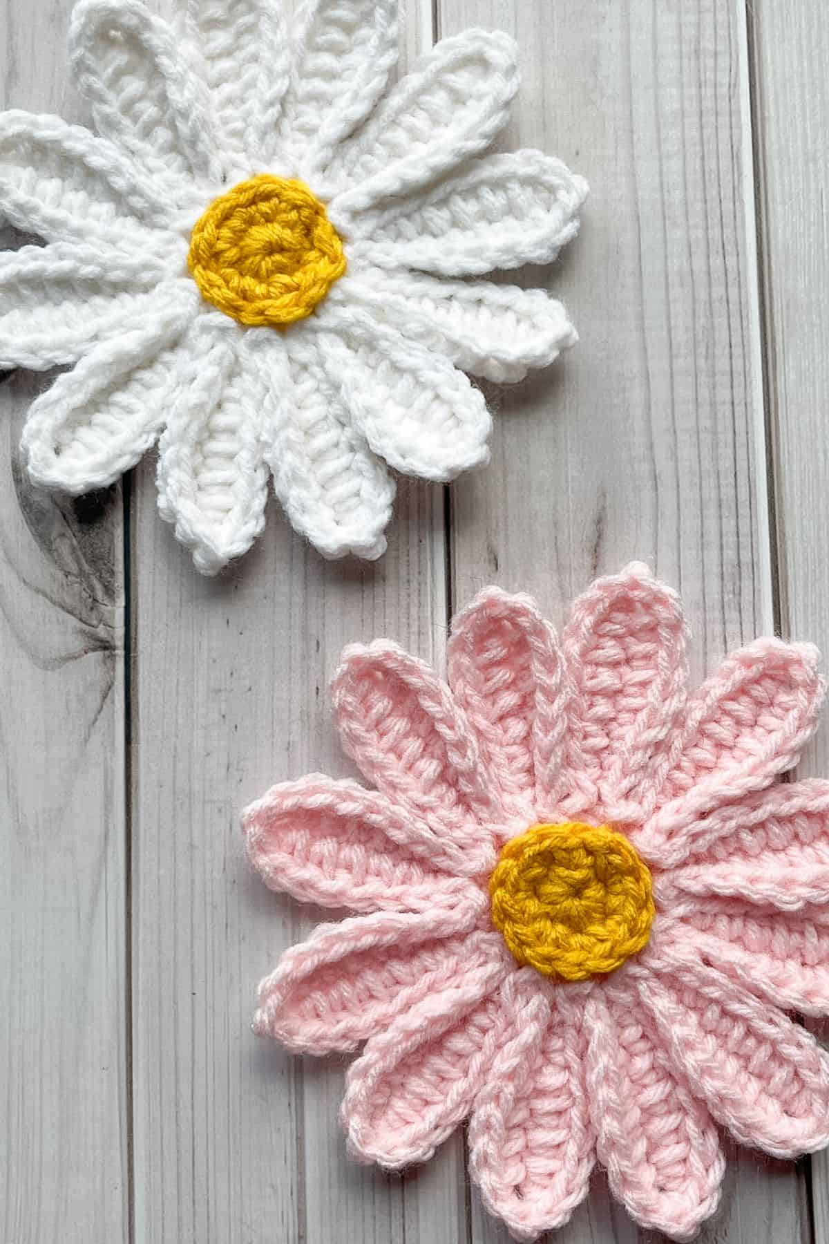 One white and one pink finished daisy appliques on the table.