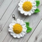 2 finished crochet daisy keychains on table.
