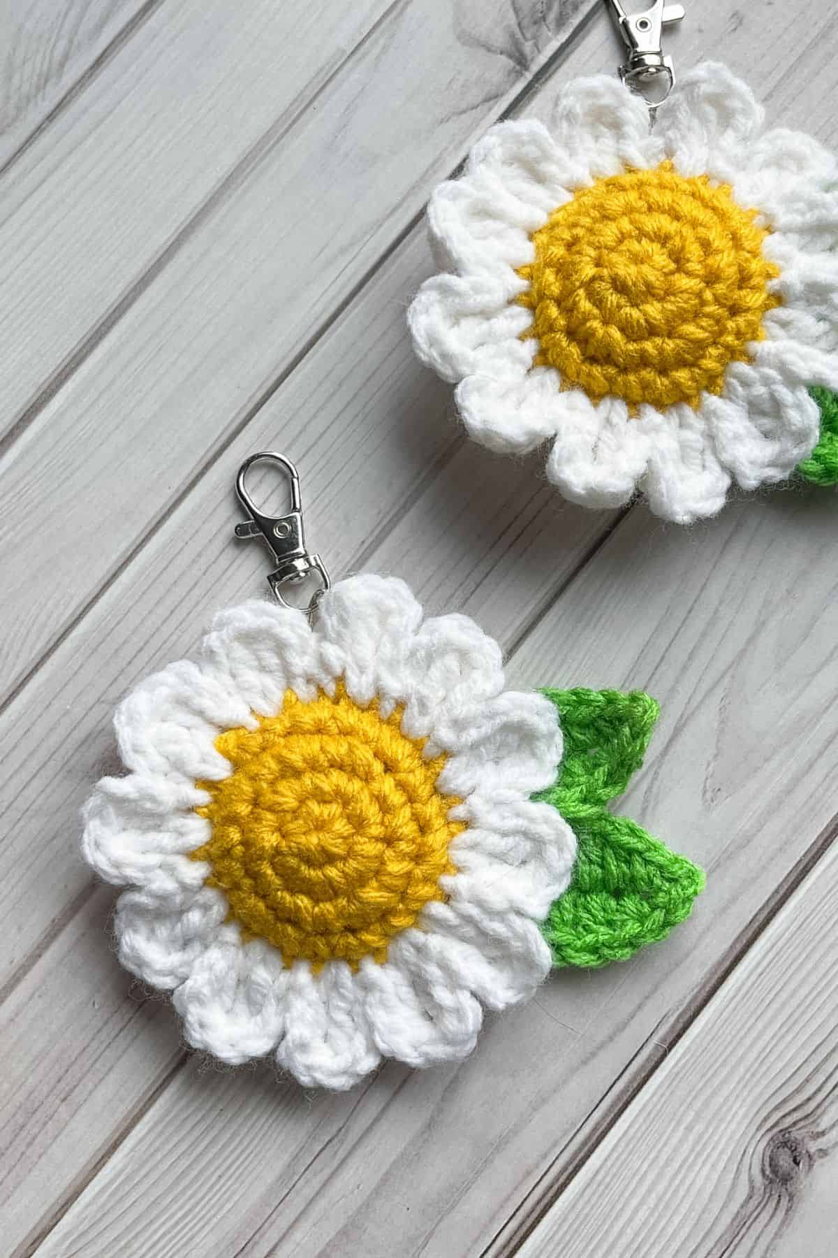 2 finished crochet daisy keychains on table.