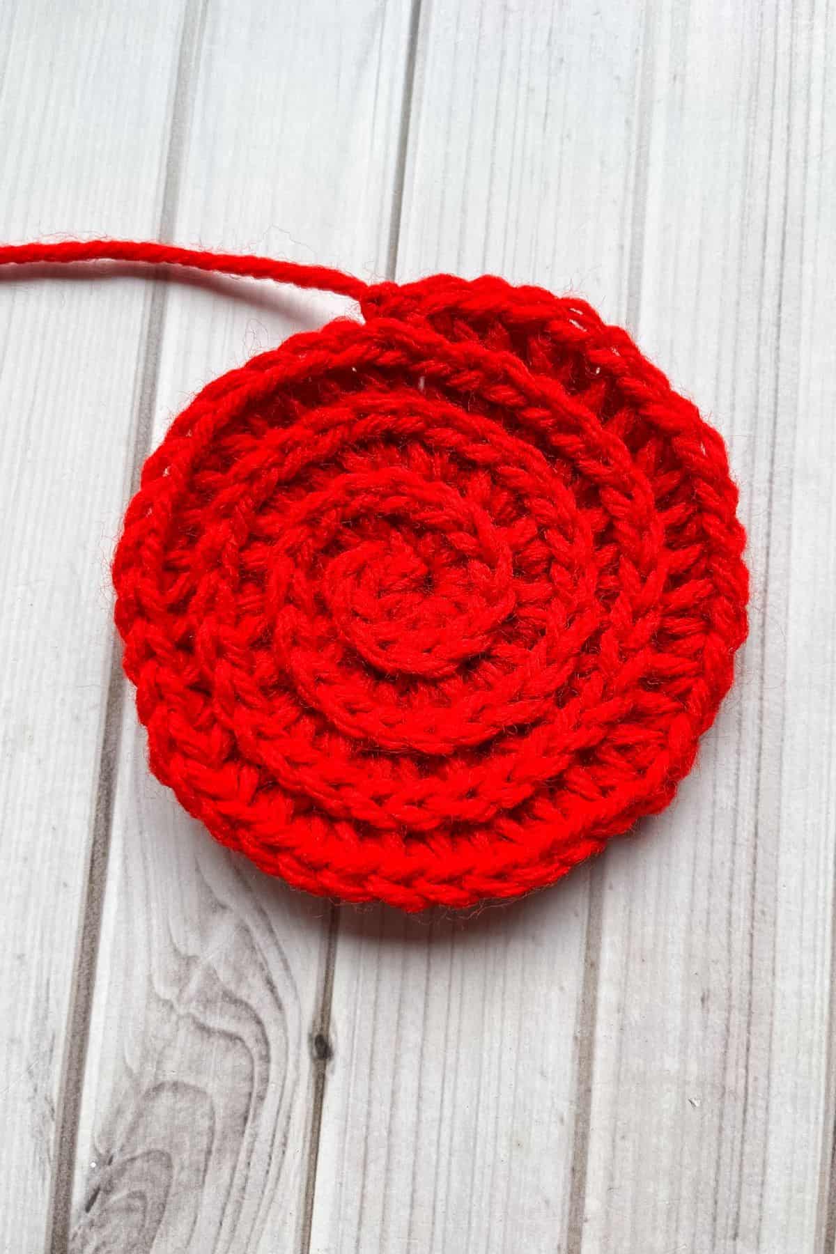 The base of the crochet rose is done, laying on a table.