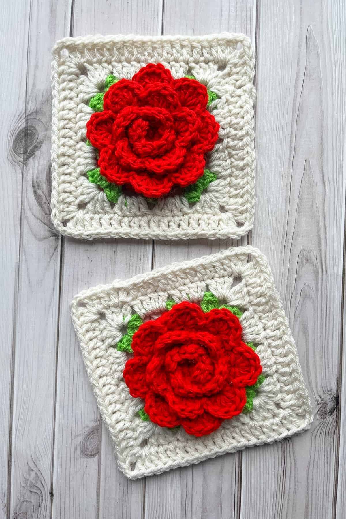 2 finished crochet rose granny squares on a wooden table.
