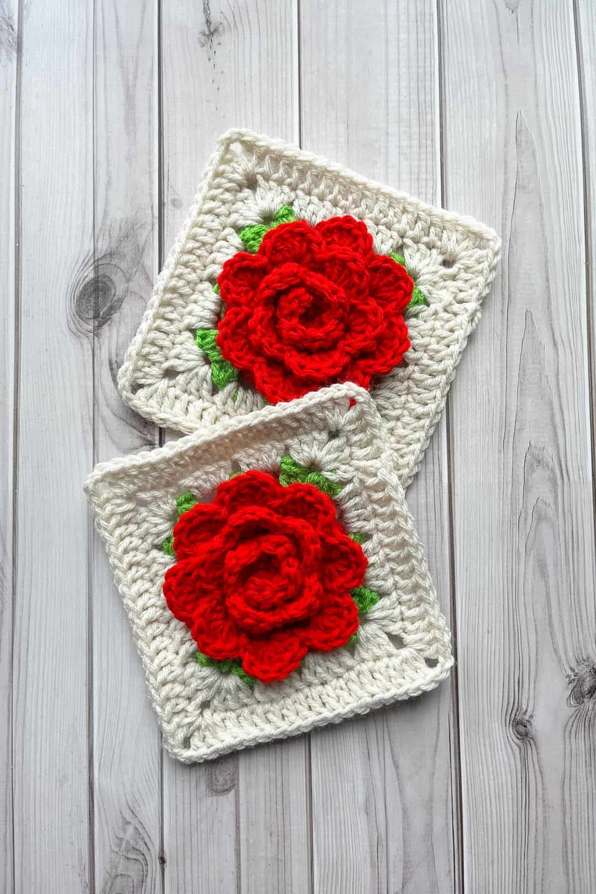 2 finished crochet rose granny squares on a wooden table, slightly overlapping.