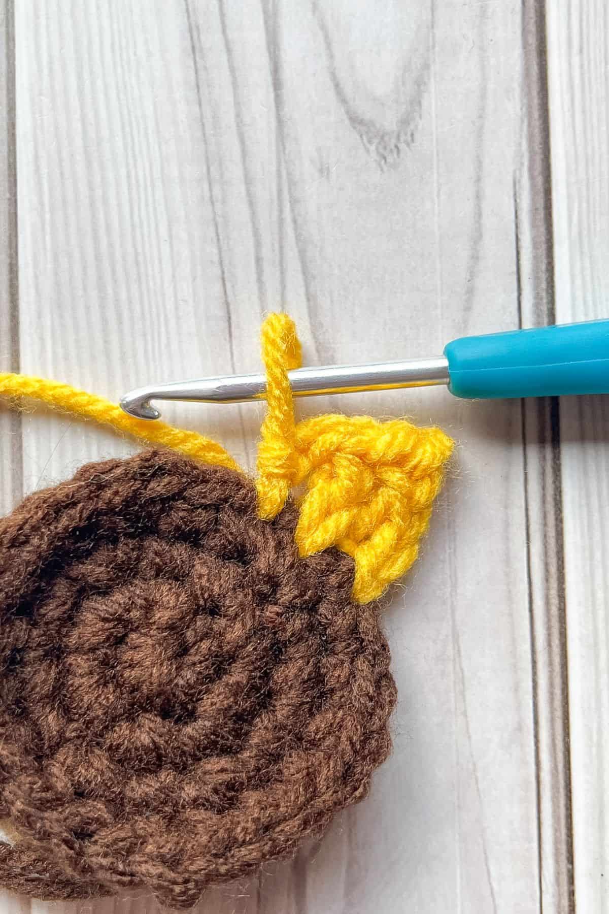 Crocheting 2 brown circles together by crocheting petals.