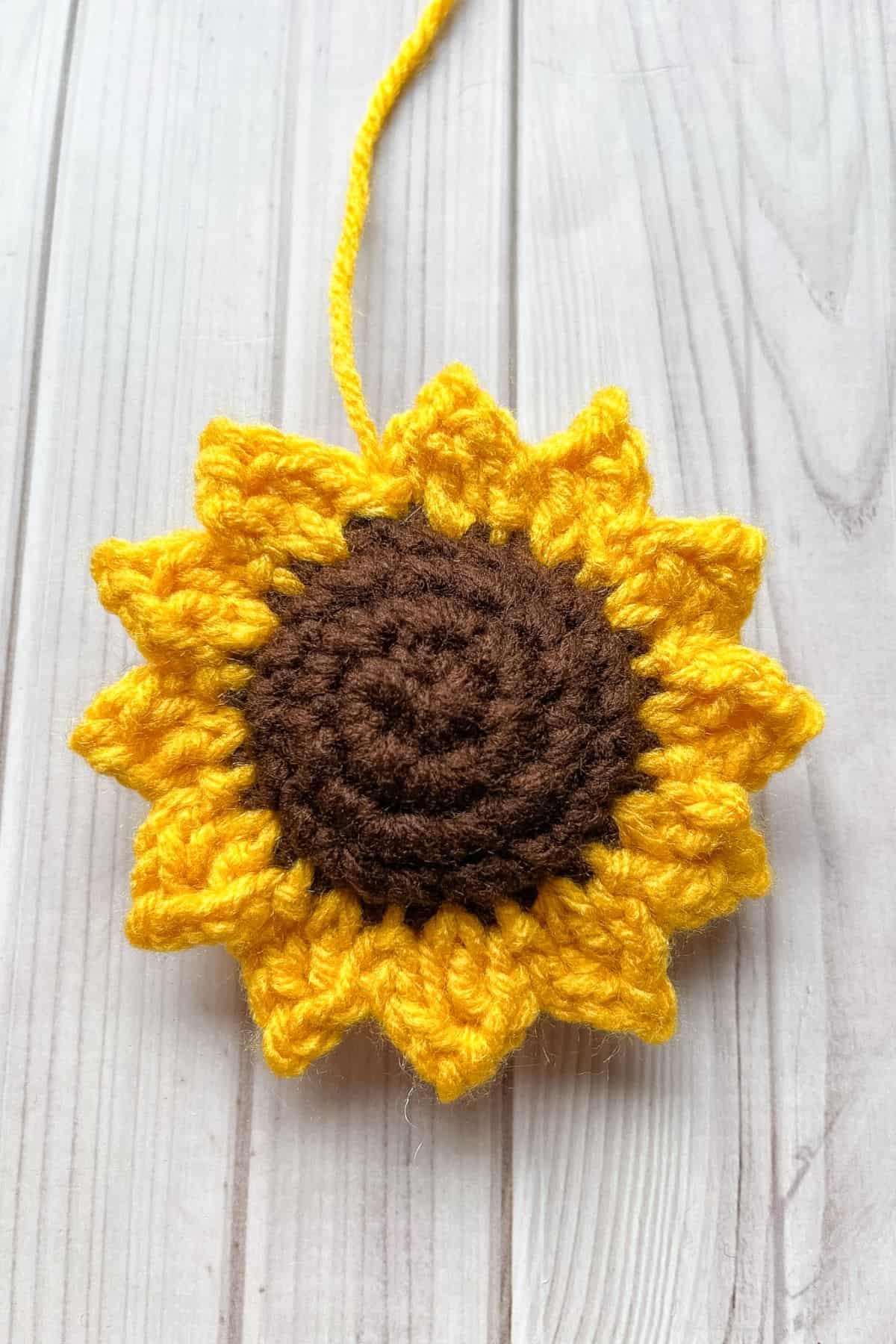 Finished crochet sunflower on the table without leaves attached.