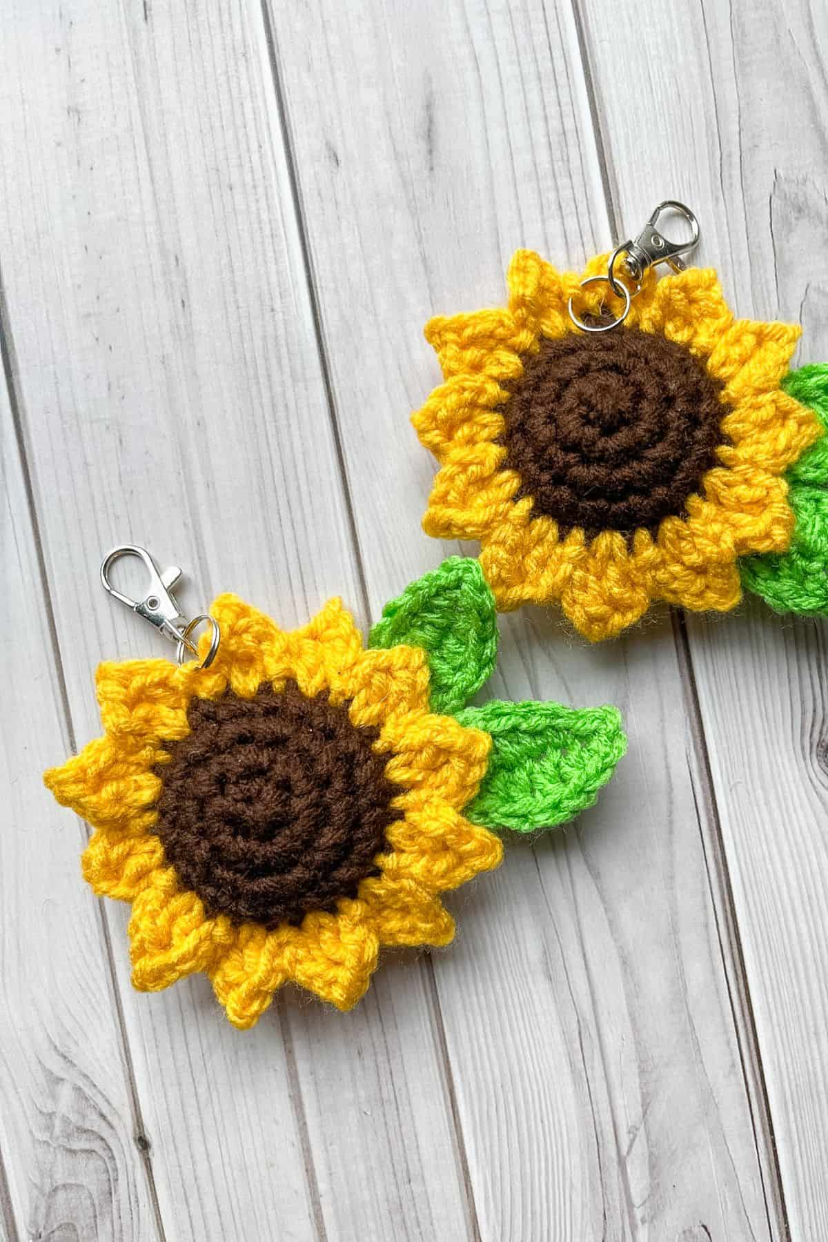 2 finished crochet sunflower keychains on table.
