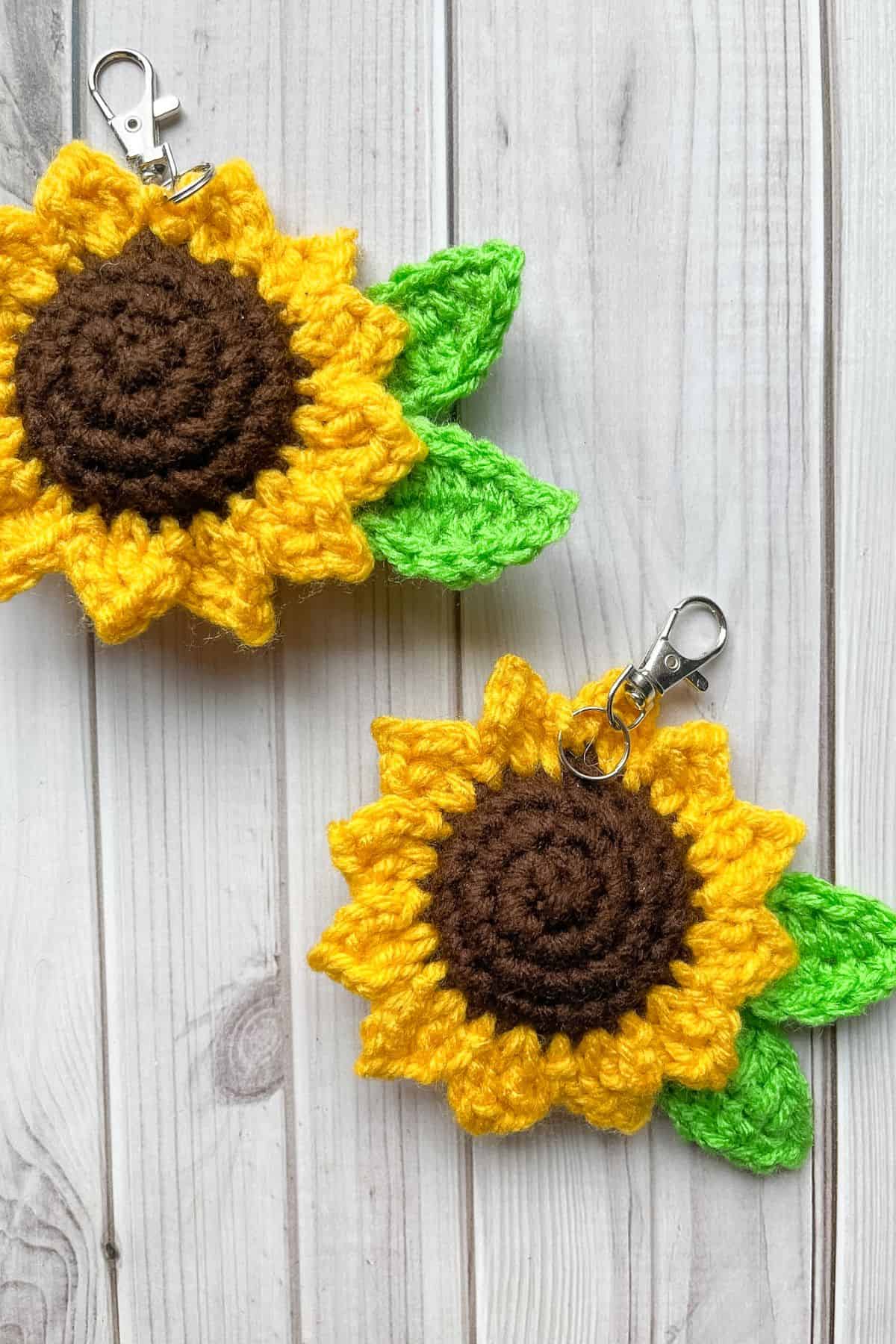 2 finished crochet sunflower keychains on table.