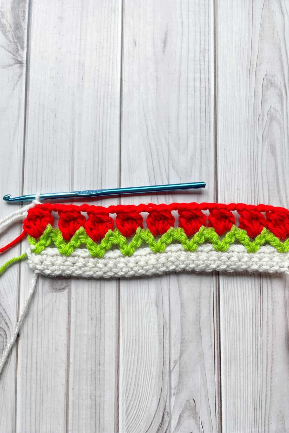 Finished row of crochet tulips, with hook on table.