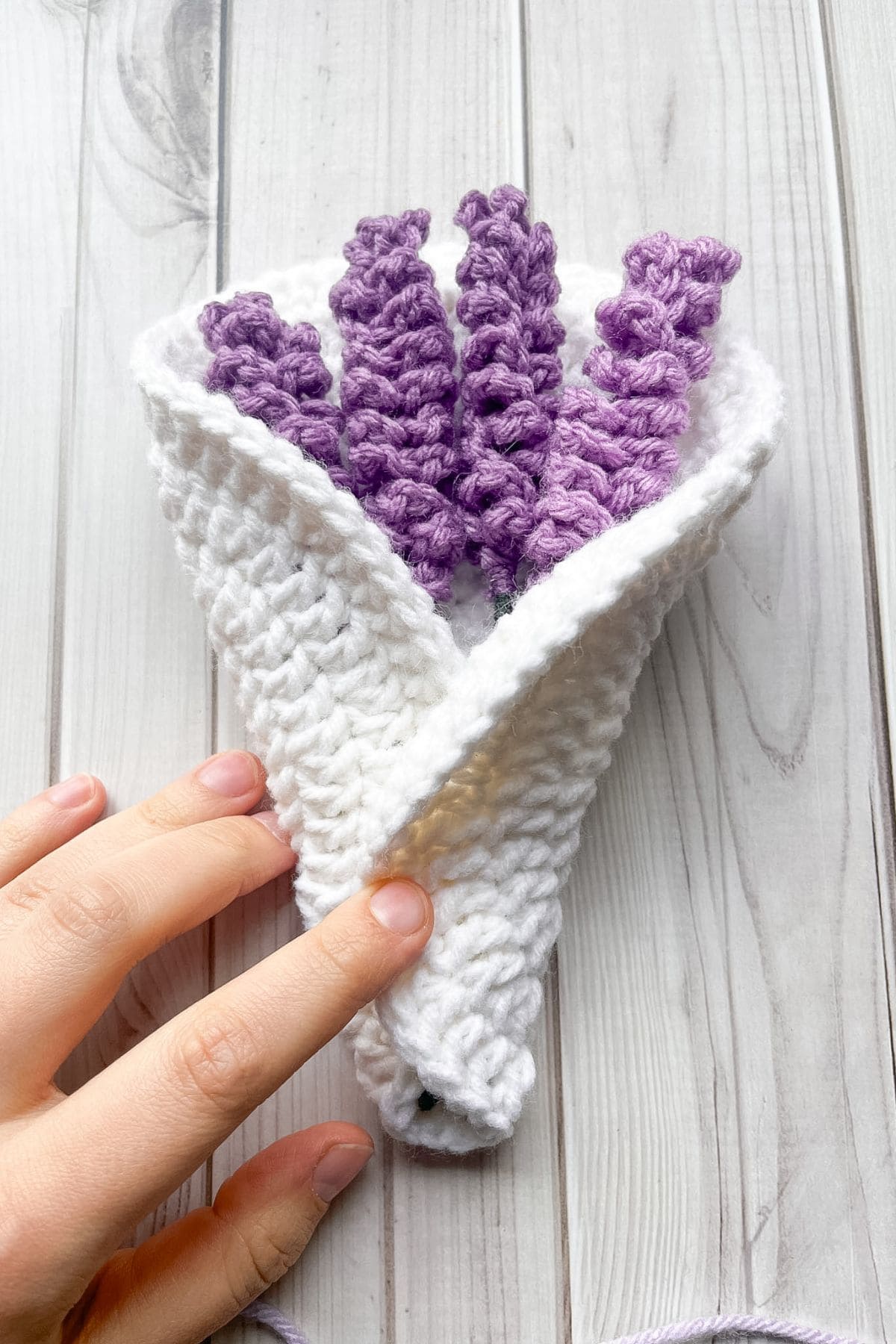 Folding the bottom of the white circle over the crochet lavender stems.