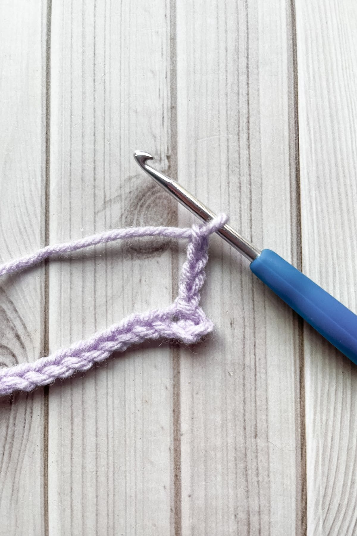 Crocheting more chains, with hook on table.
