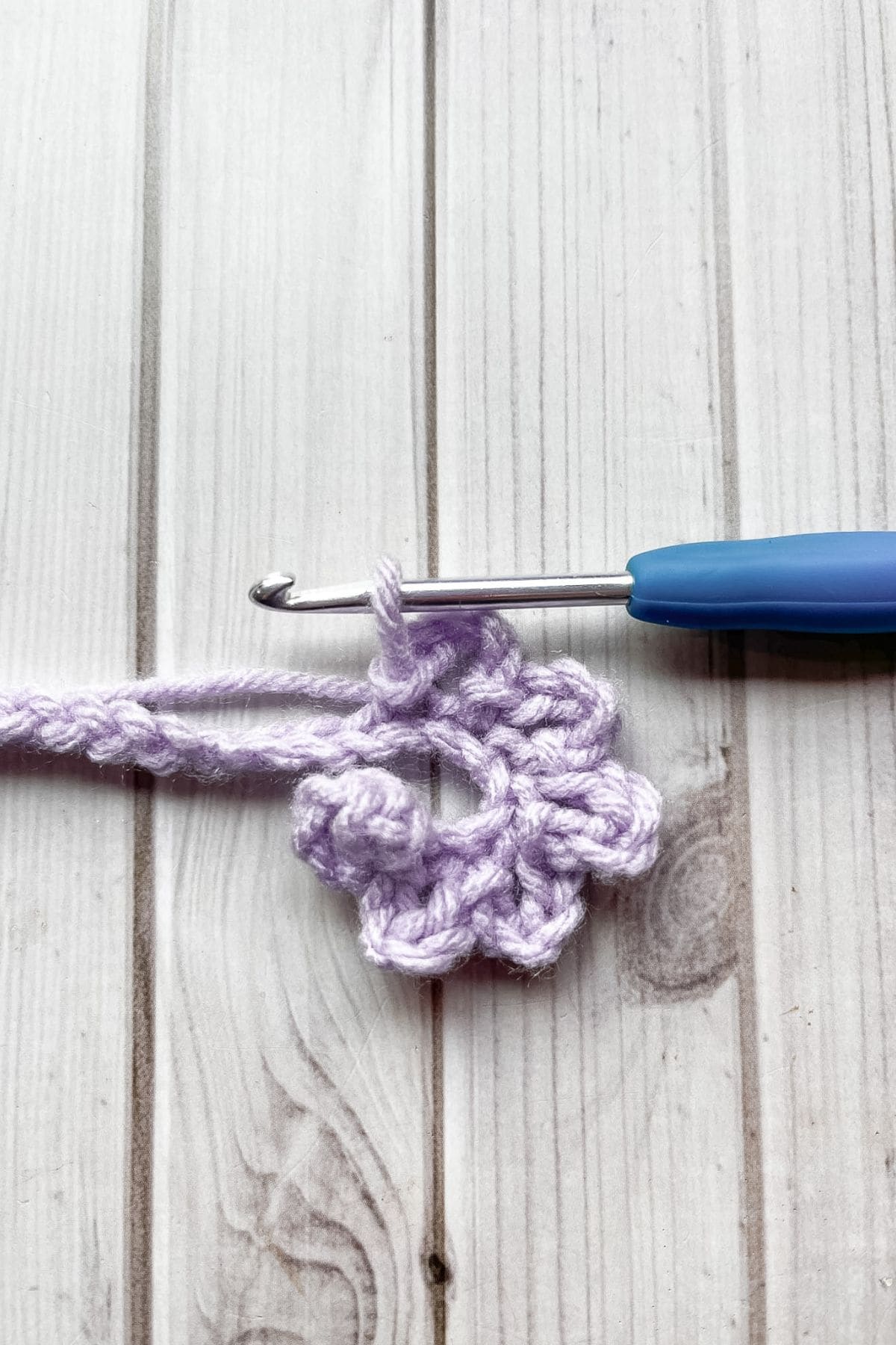Crocheting more petals, with hook on table.