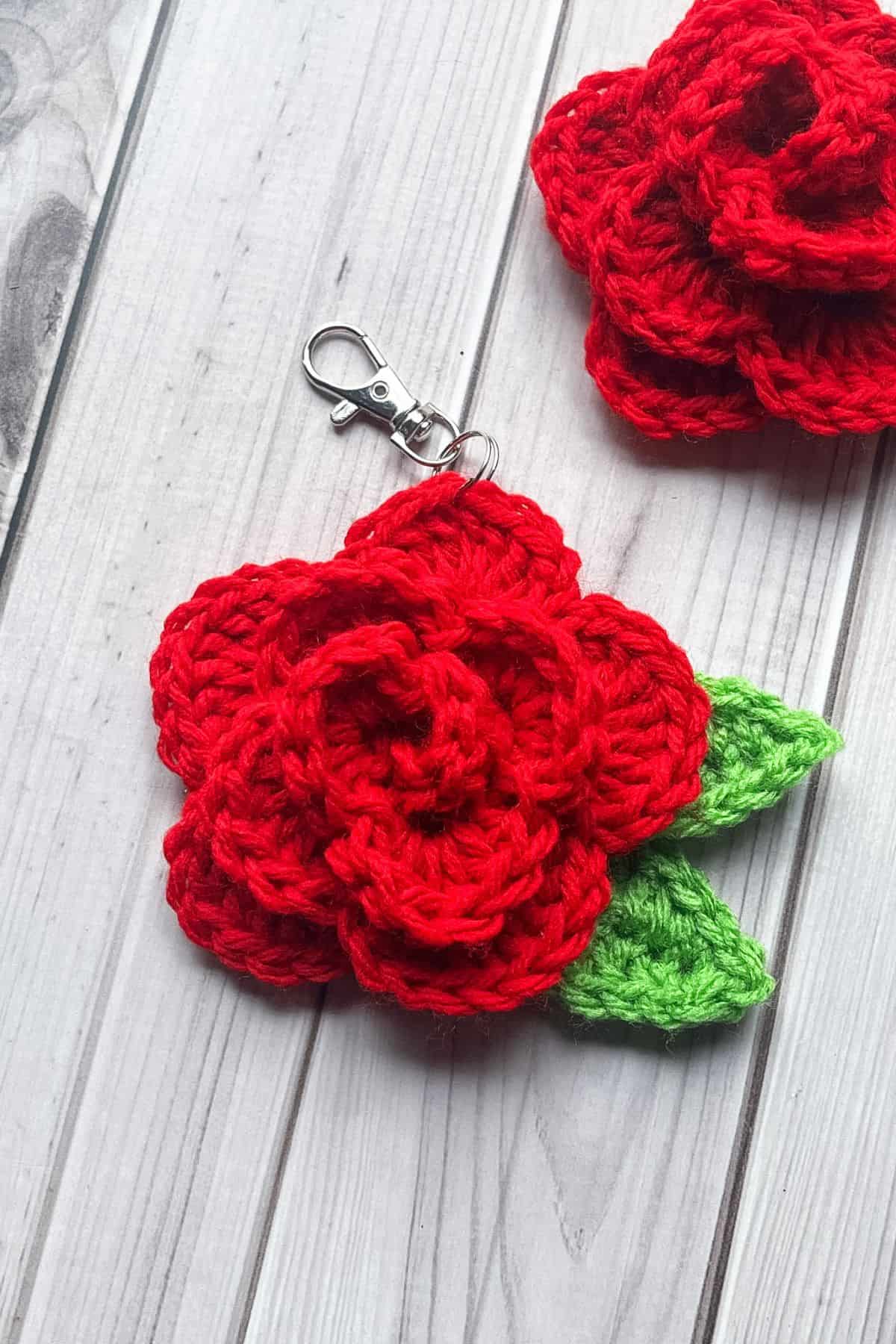 2 finished crochet rose keychains on the table.