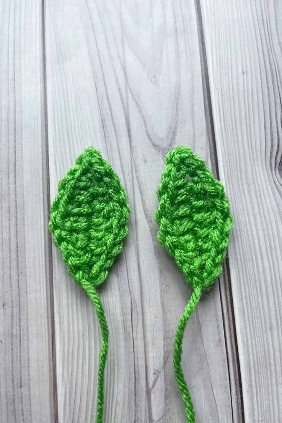 2 crochet leaf's lay on a table.