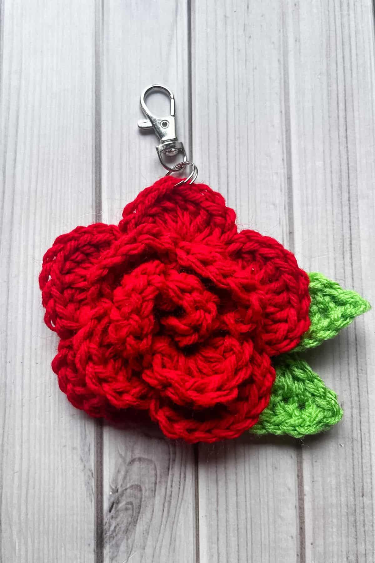 A finished crochet rose lay on a table.