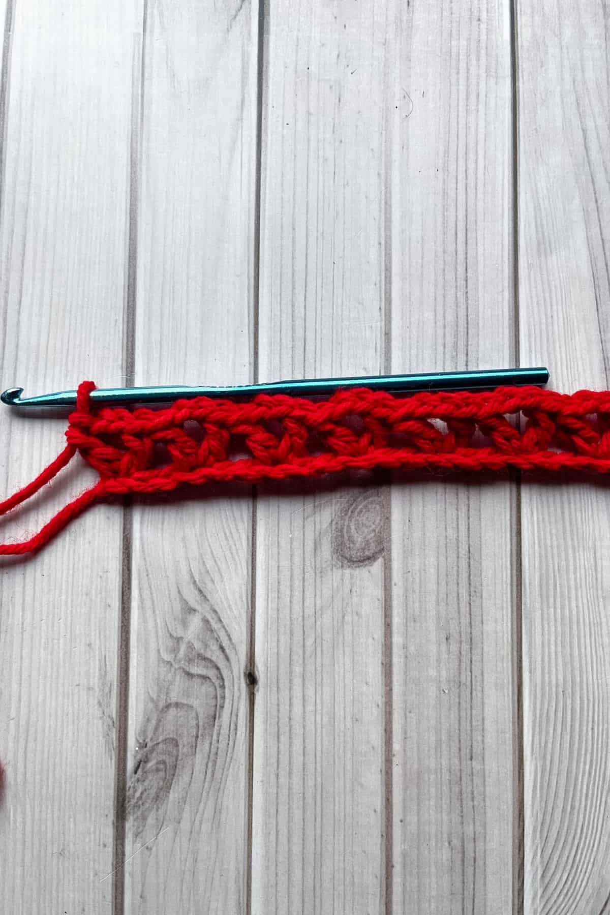 Full row of crochet V stitches completed and laying on a table.