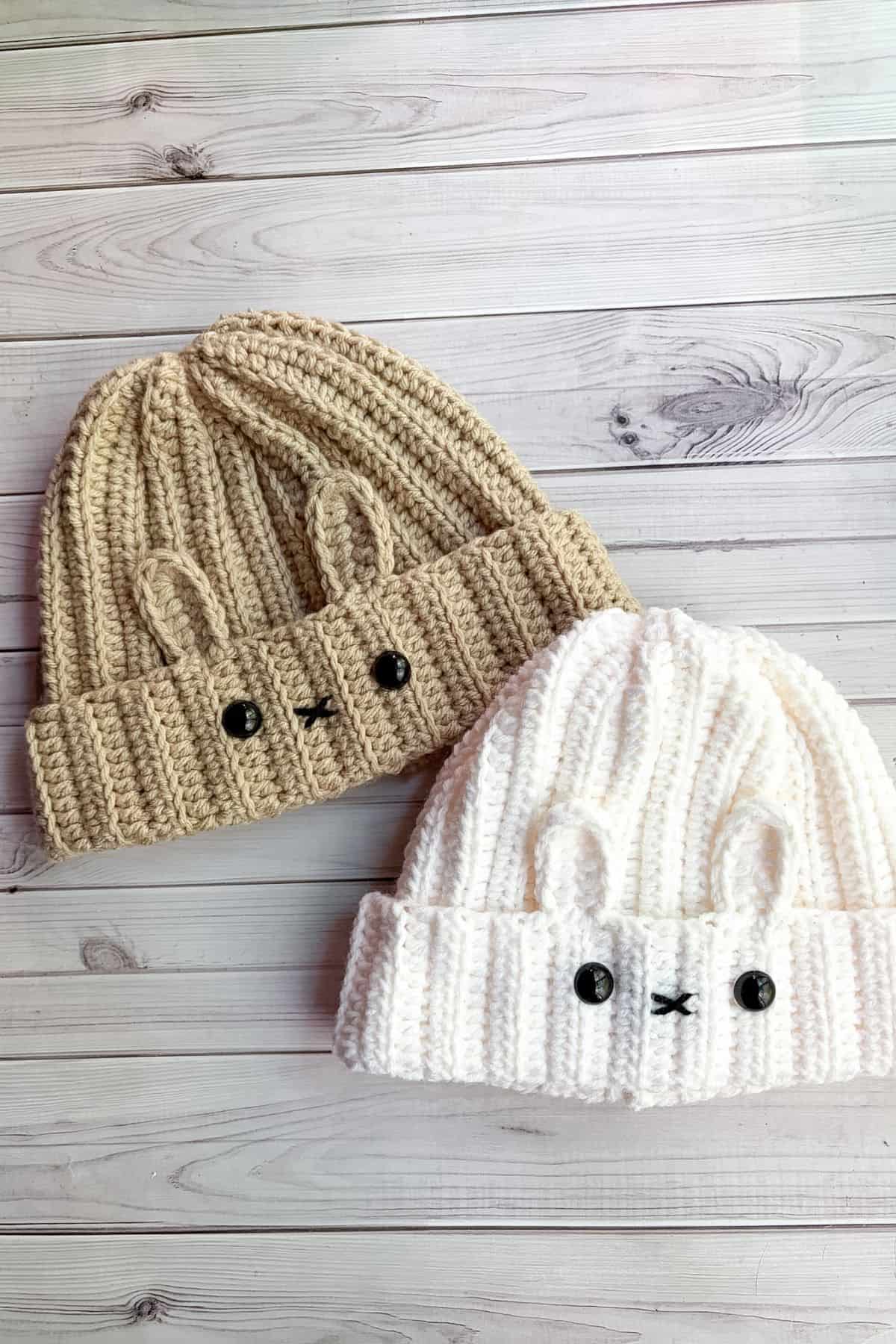 2 finished crochet bunny hats on table.