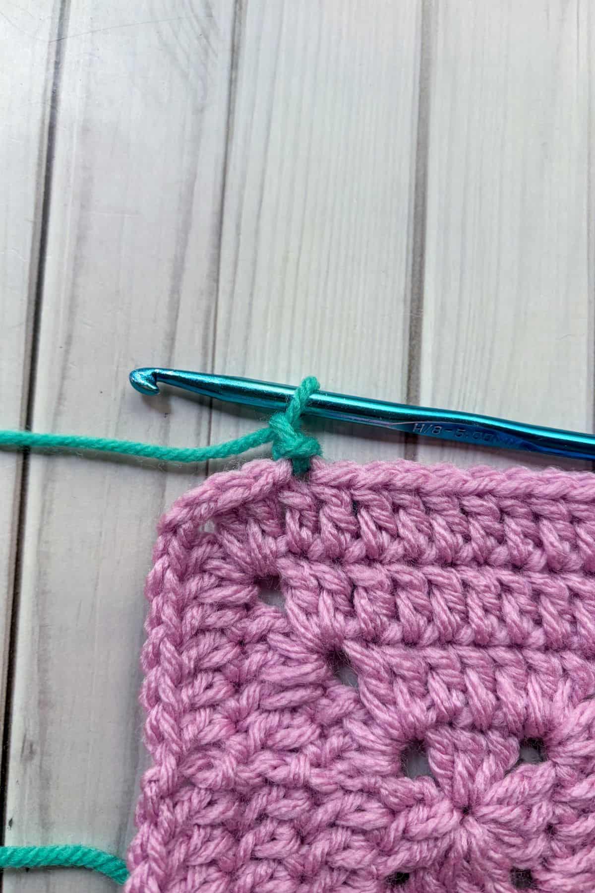Joining the teal yarn to the granny square.