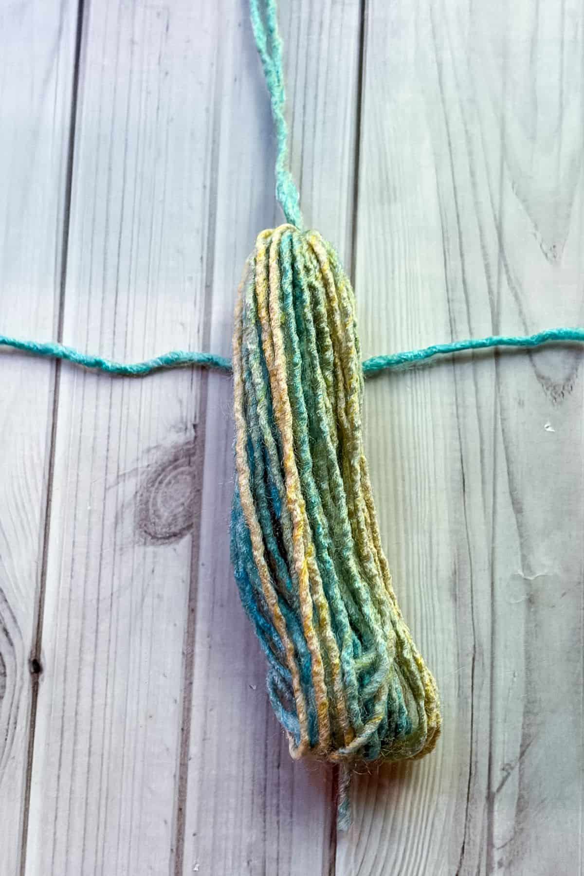 Putting tassel on top of a short piece of yarn.