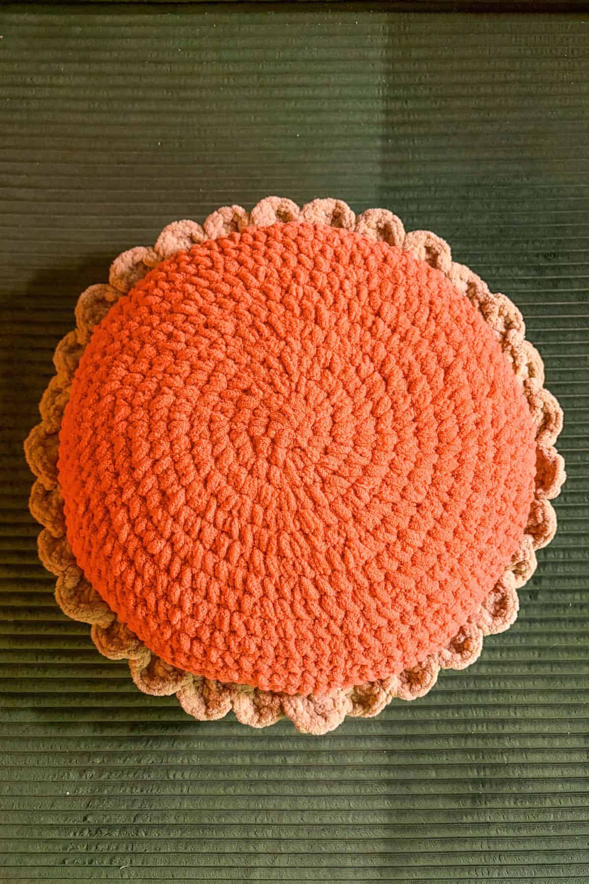 Finished crochet pumpkin pillow on couch, minus the whipped cream.