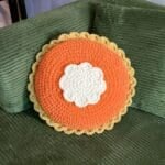 Finished crochet pumpkin pillow on couch.