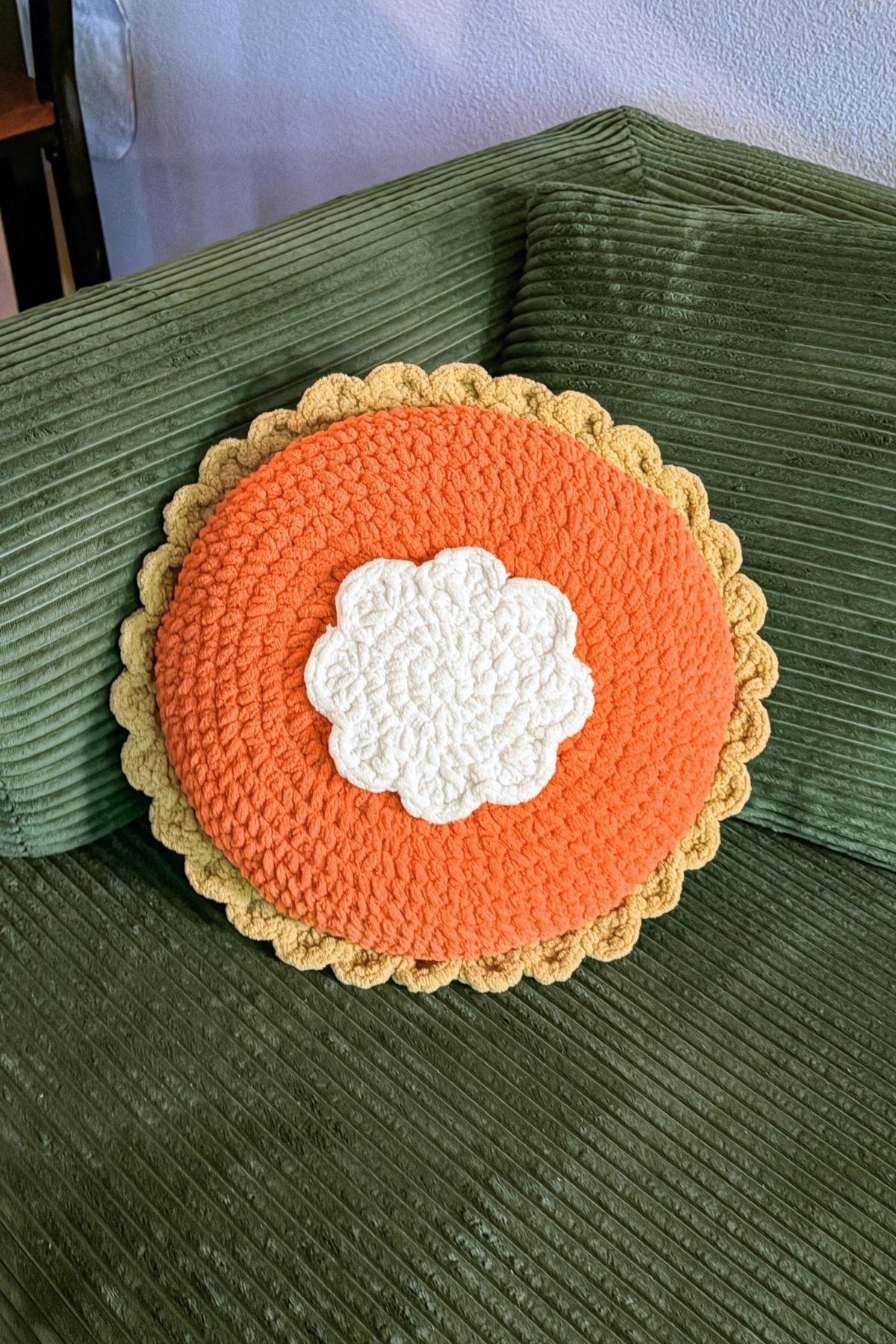 Finished crochet pumpkin pillow on couch.
